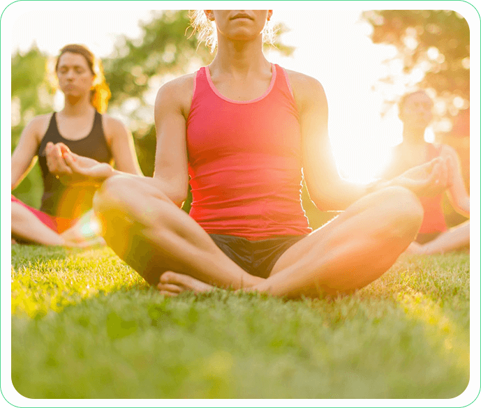 A group of people sitting in the grass doing yoga.